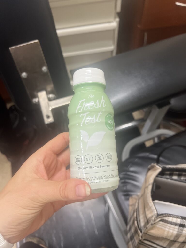 Dietitian holding The Fresh Test 50g glucose drink before her gestational diabetes screening at 25 weeks pregnant
